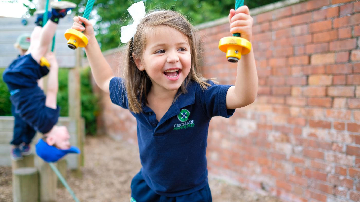A smiling Reception pupil enjoying the trim trail at school. Enjoying going back to school.
