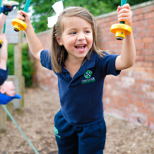 A smiling Reception pupil enjoying the trim trail at school. Enjoying going back to school.