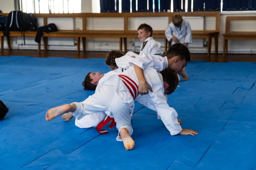 Judo Club in full swing. A group of pupils practicing their throws and grappling techniques. Working towards their next belt.