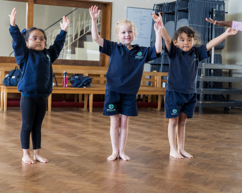 Three girls enjoying Cricklade Manor Preps Ballet Club. They are holding their arms in the air, smiling.