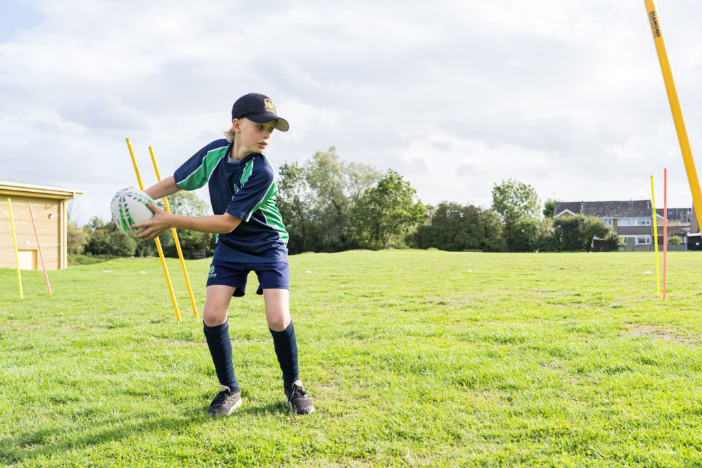 A young rugby player at Cricklade Manor Prep's rugby club is about to pass the ball during a game.